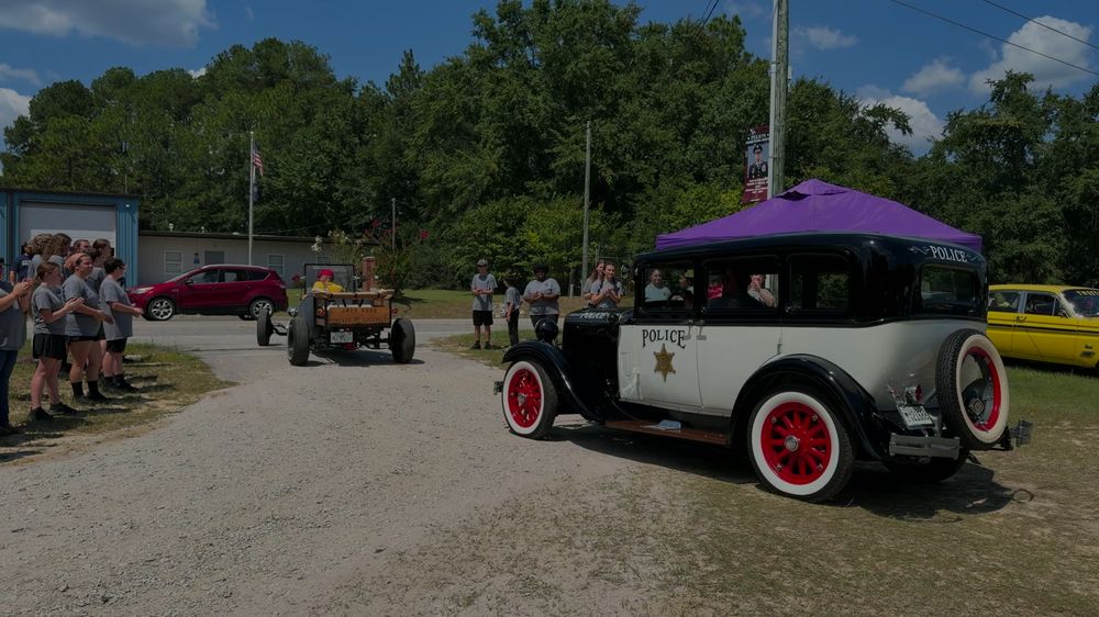 Model A police car rolling past the band students